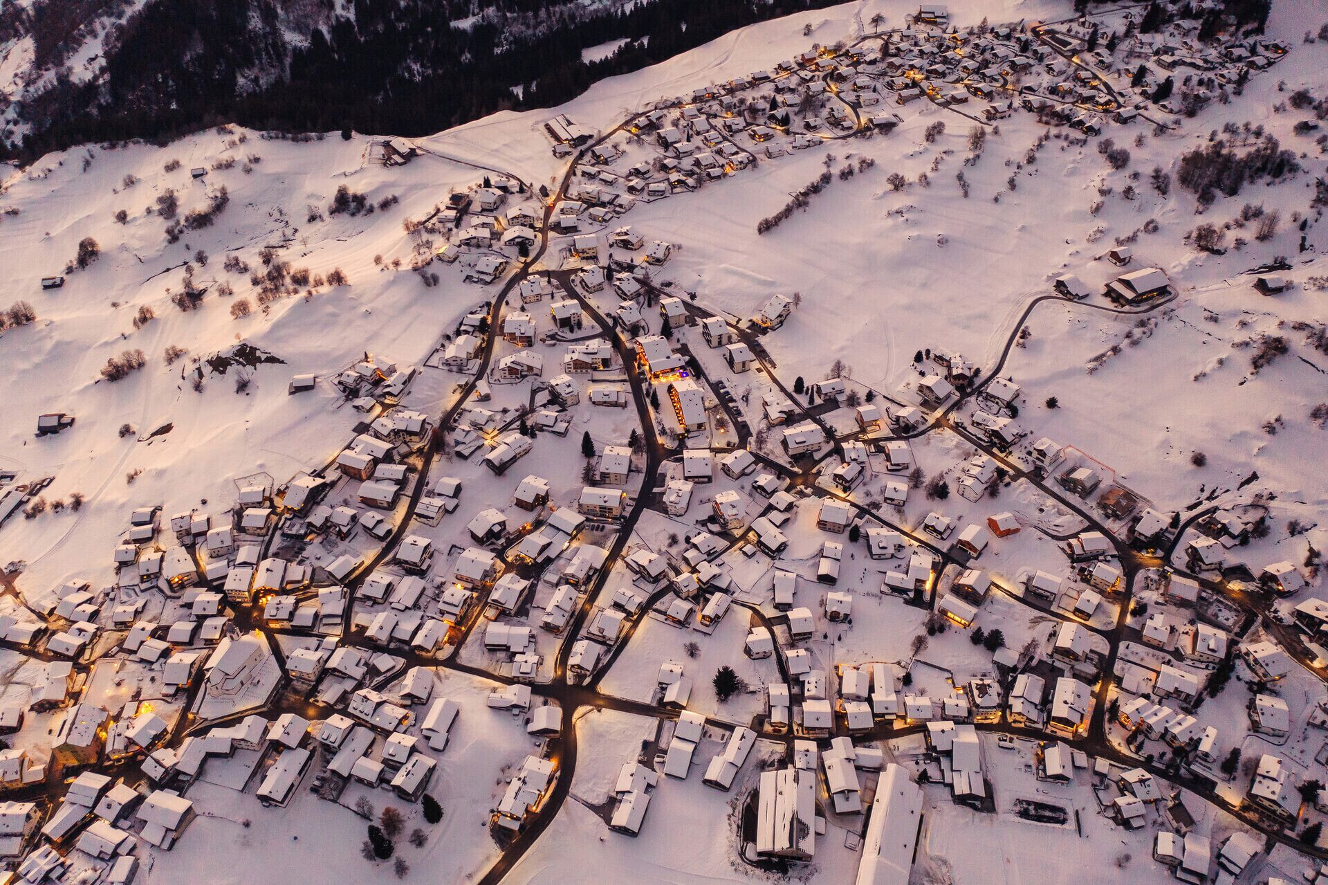 An aerial view of a snow-covered town with a grid of houses and roads.