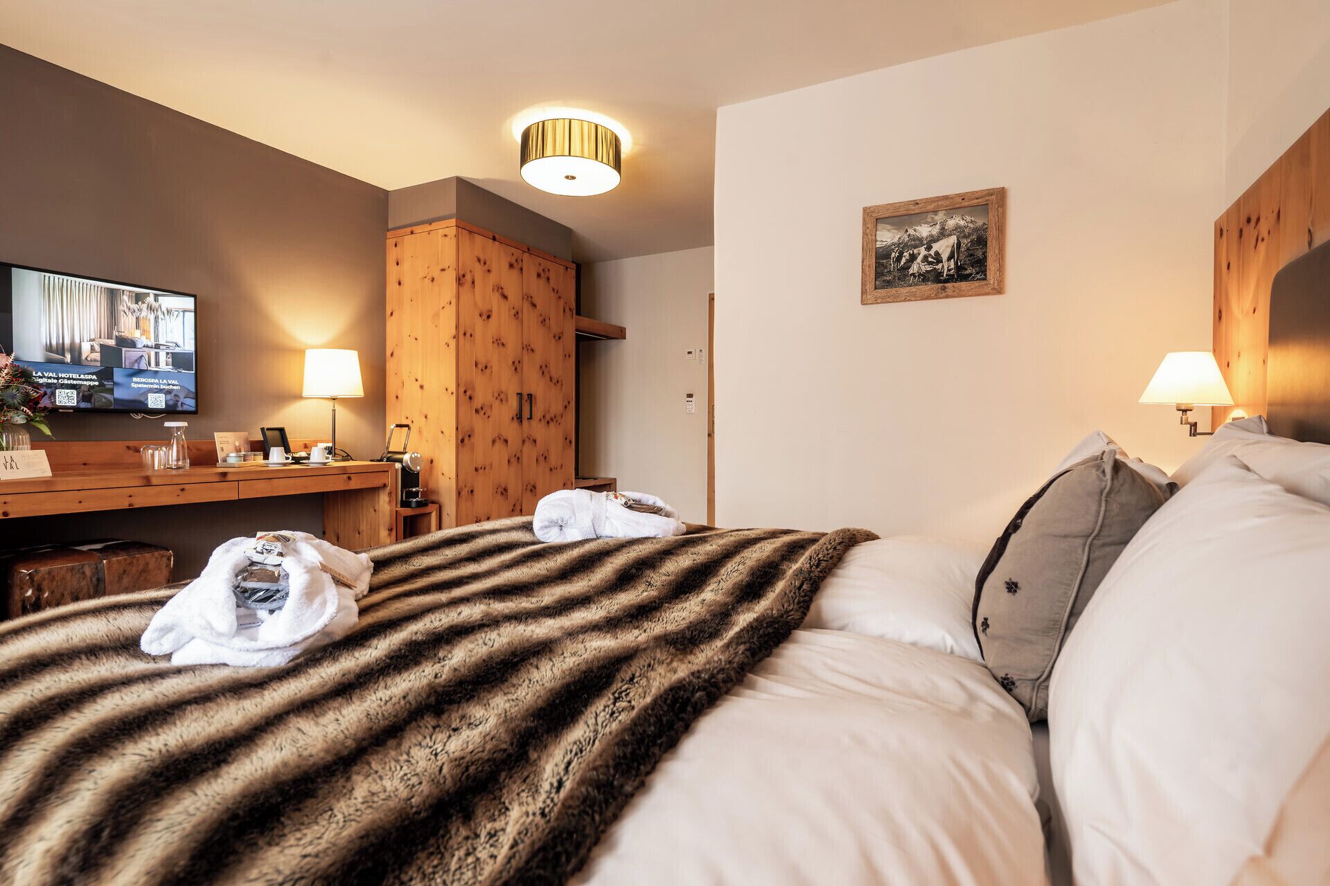 Una habitación de hotel con una cama, un escritorio, un televisor y un armario de madera.