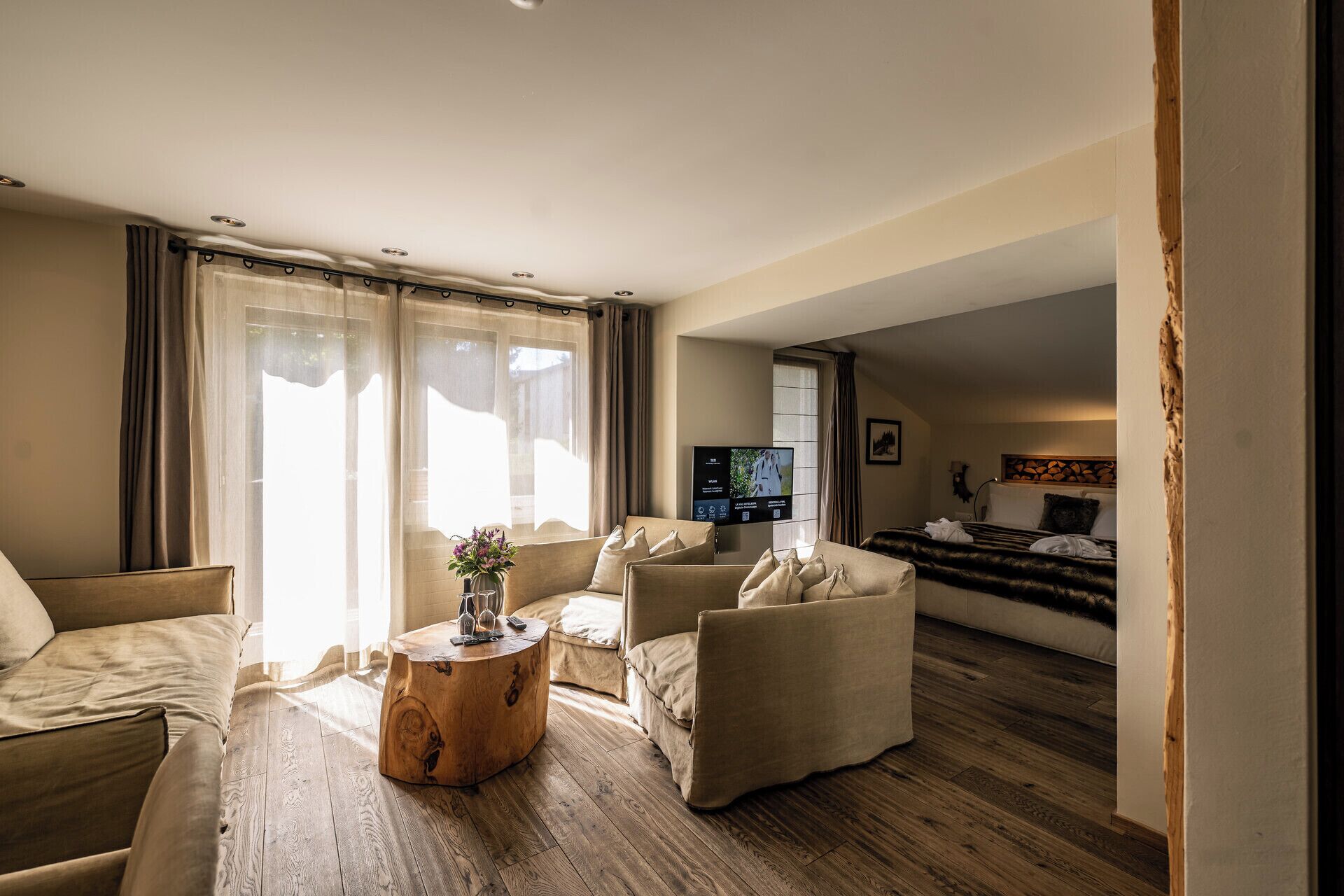 A modern hotel room with a living area, a wooden coffee table, and a bed with a headboard.