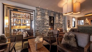 A modern interior with stone walls, leather furniture, and a bar area with liquor bottles. - La Val Hotel & Spa (Brigels)