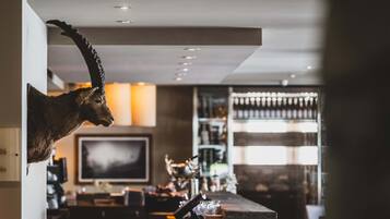 A room with a mounted animal head on the wall, a bar area with glasses and bottles, and a television in the background.