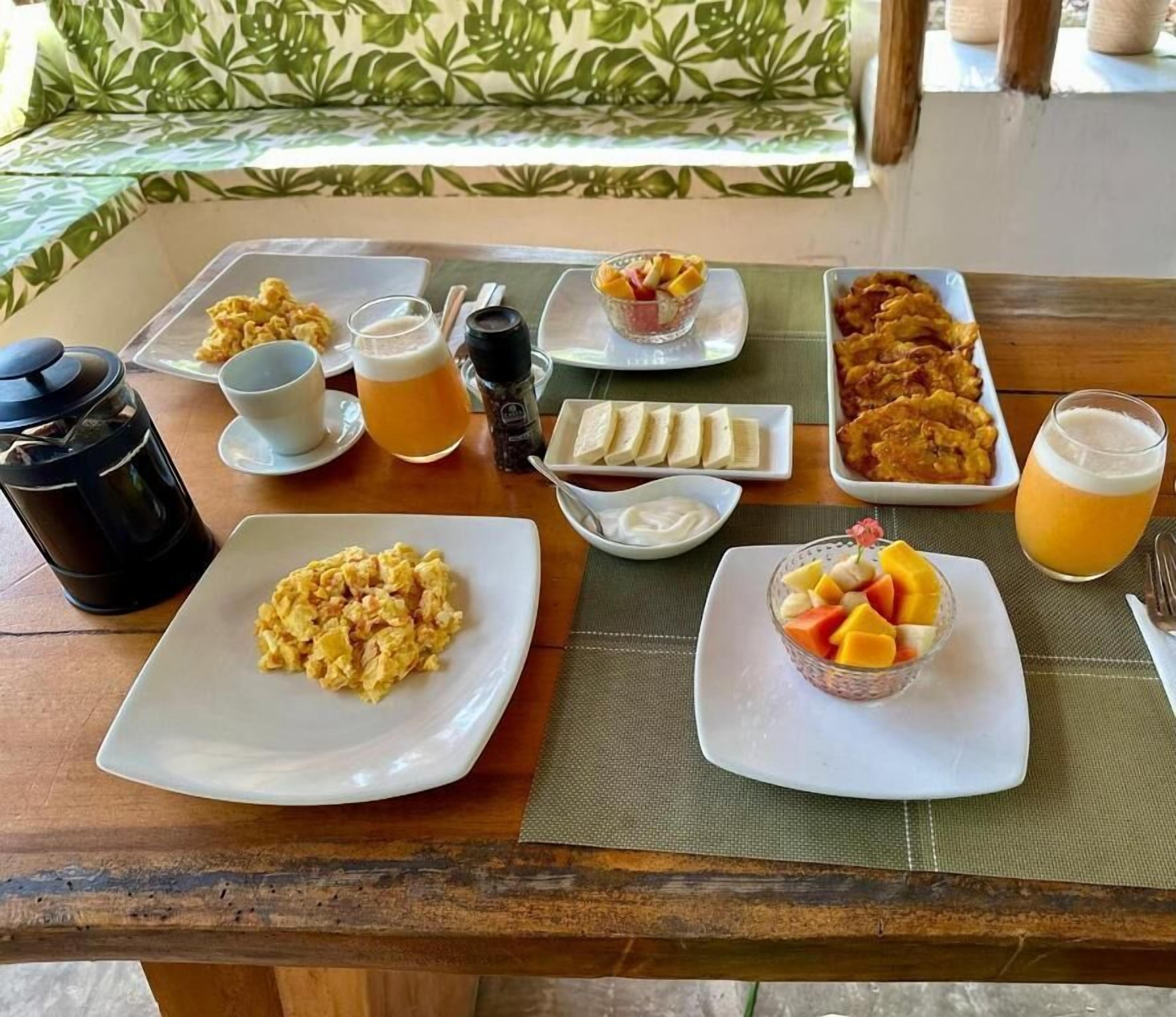 A breakfast table with various dishes including scrambled eggs, fruit, and beverages.