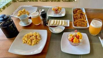 A breakfast table with various dishes including scrambled eggs, fruit, and beverages.