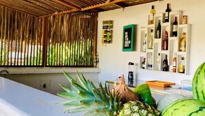 Une pièce avec un plafond en bois, un mur blanc orné d’une étagère à vin et une fenêtre donnant sur un paysage verdoyant.