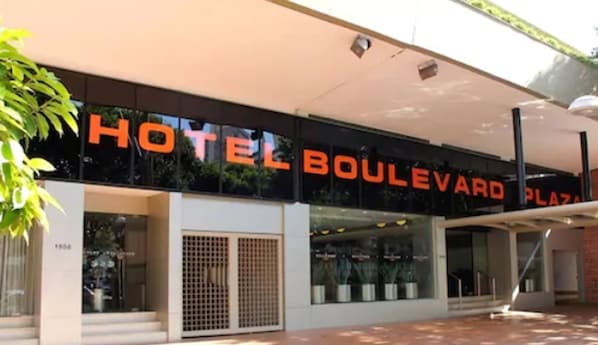 Un hotel llamado 'Hotel Boulevard Plaza' con una fachada moderna, ventanas grandes y un acceso cubierto.