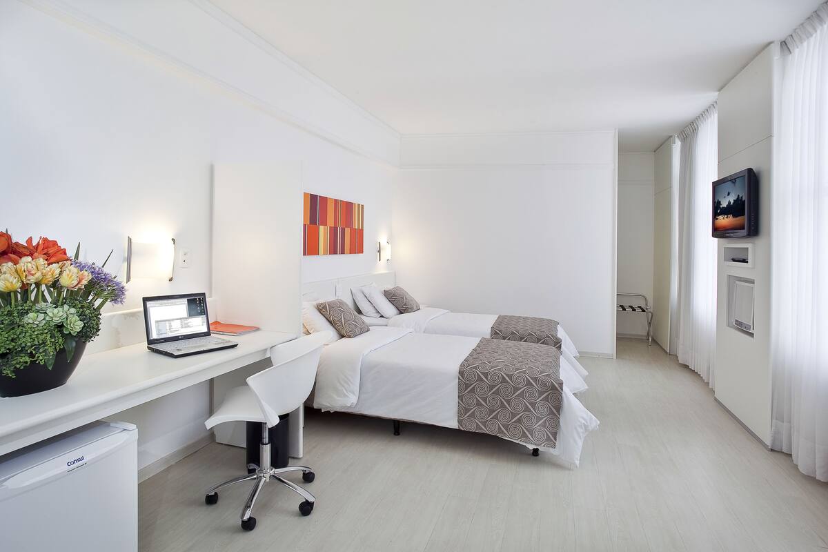 Une chambre d’hôtel moderne équipée d’un bureau, d’un ordinateur portable et d’un lit avec une literie à motifs.