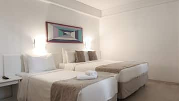 Una habitación de hotel con dos camas, una mesita de noche con lámpara y un cuadro en la pared.