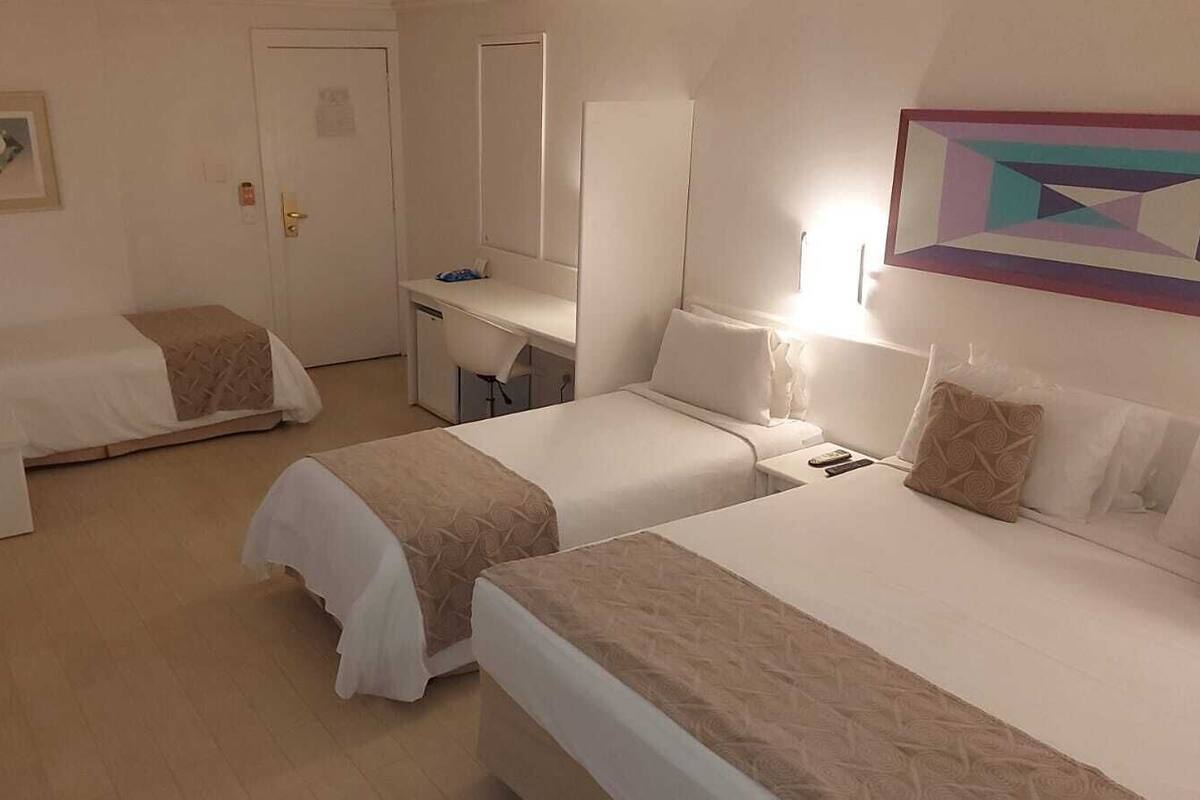 Une chambre d’hôtel avec deux lits simples, un bureau, une chaise et une petite table.