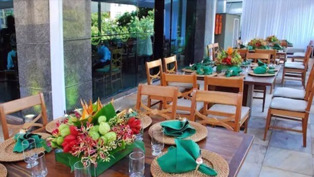 Comedor con mesas y sillas de madera, dispuesto para una comida.