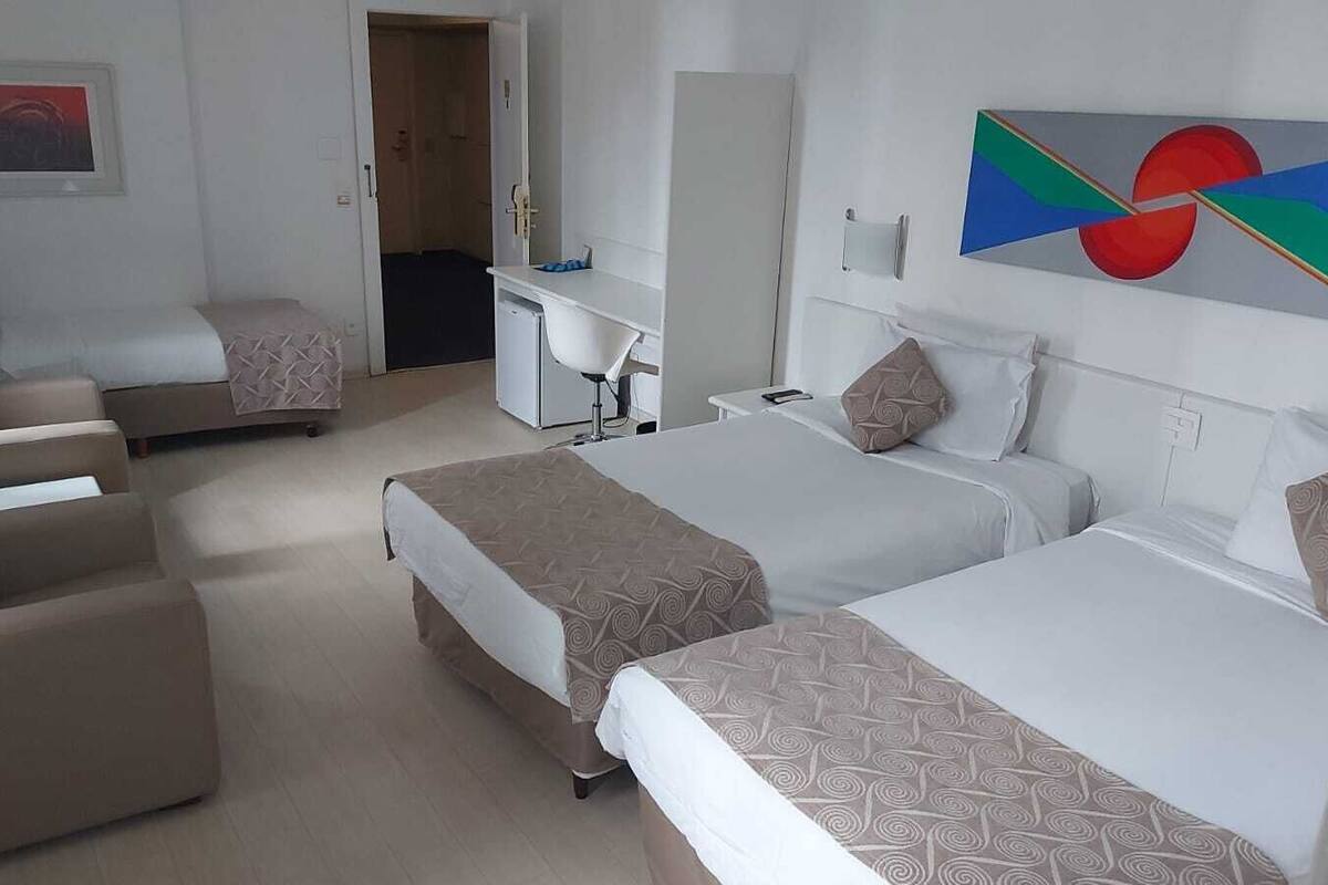 Une chambre d’hôtel avec deux lits, un bureau, une chaise et une porte.