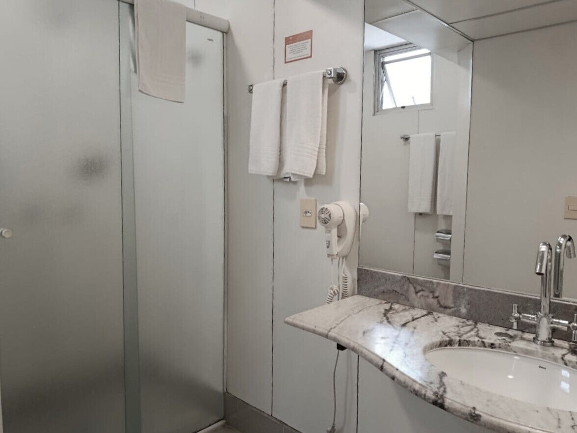 Un baño con lavamanos de mármol, un secador de pelo y dos toallas colgadas en la pared.