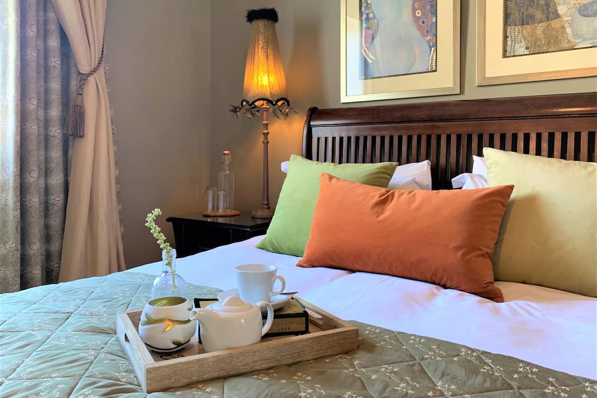 Un lit bien fait, avec des oreillers, une table de chevet avec une lampe et un plateau avec un service à thé.