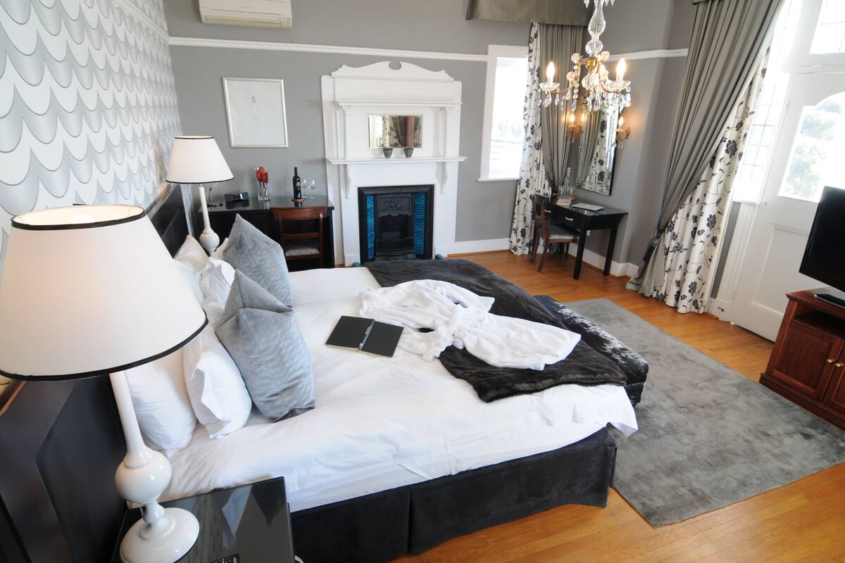 Une chambre à coucher comprenant un lit, une table de chevet, une lampe, une cheminée et un téléviseur.