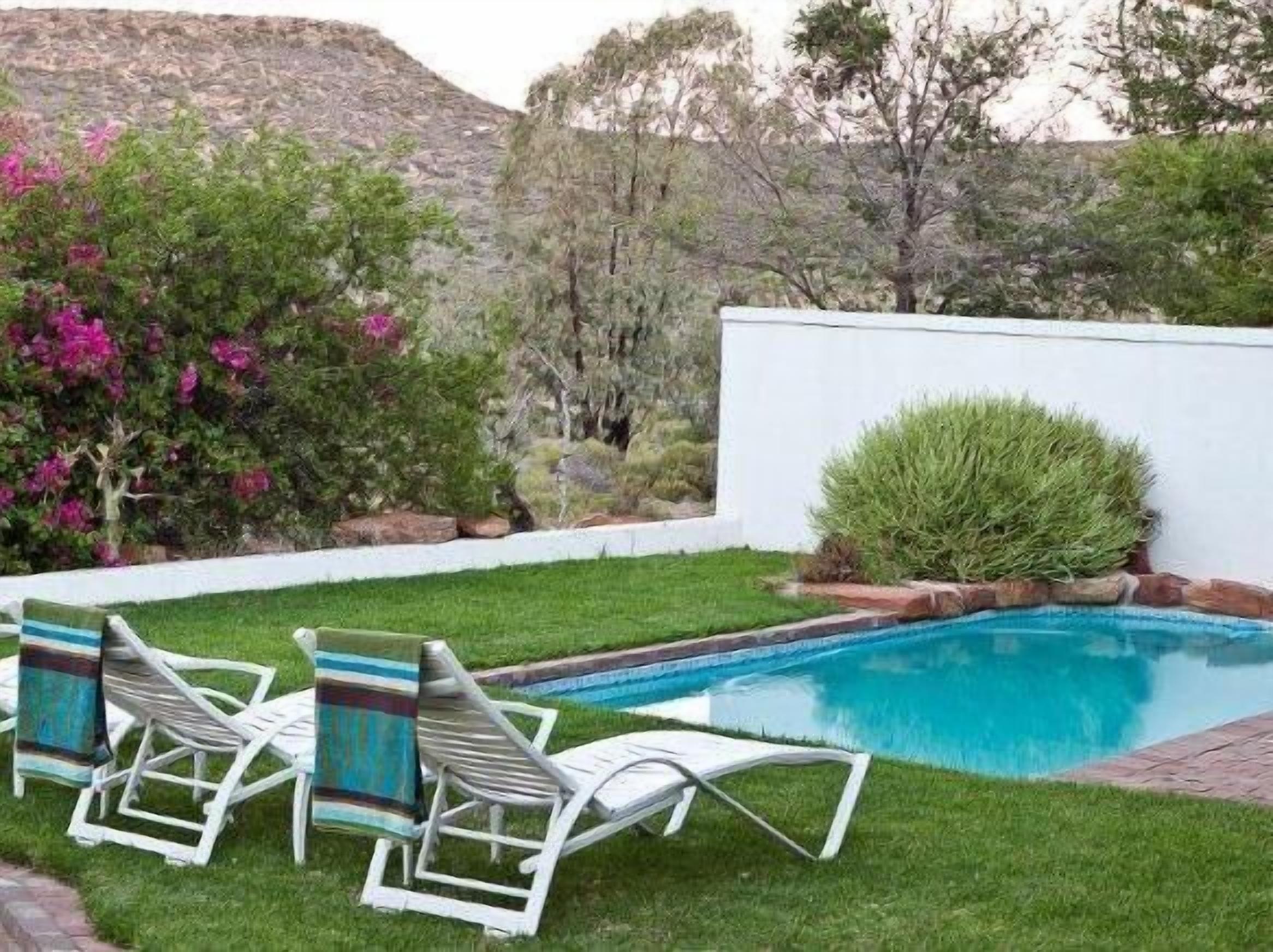 Een buitenzwembad, parasols bij het zwembad en ligstoelen