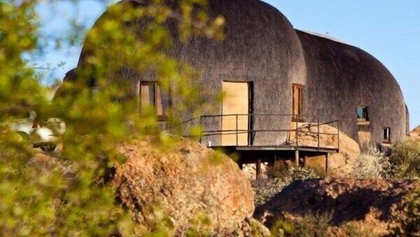 Un bâtiment en forme de dôme, doté d’un toit plat, de grandes fenêtres et d’une terrasse en bois.