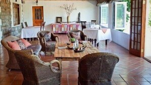 Un coin repas rustique avec des meubles en osier, une table en bois et un mur en pierre.