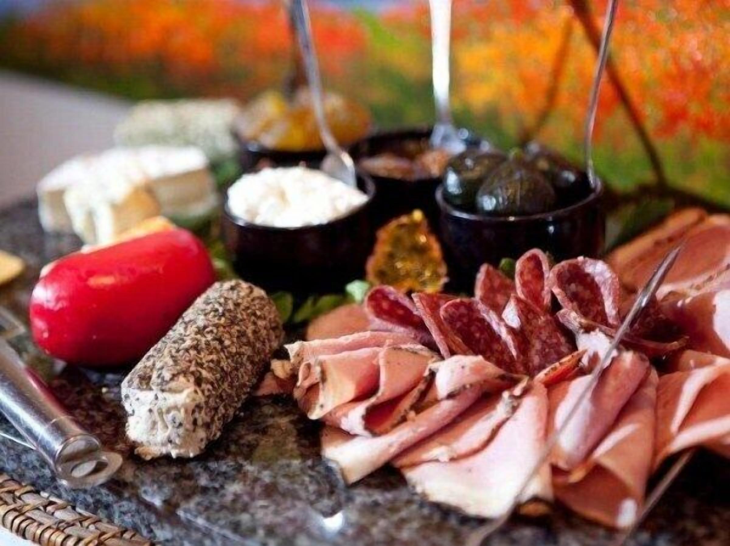 A charcuterie board with various meats, cheeses, and condiments.