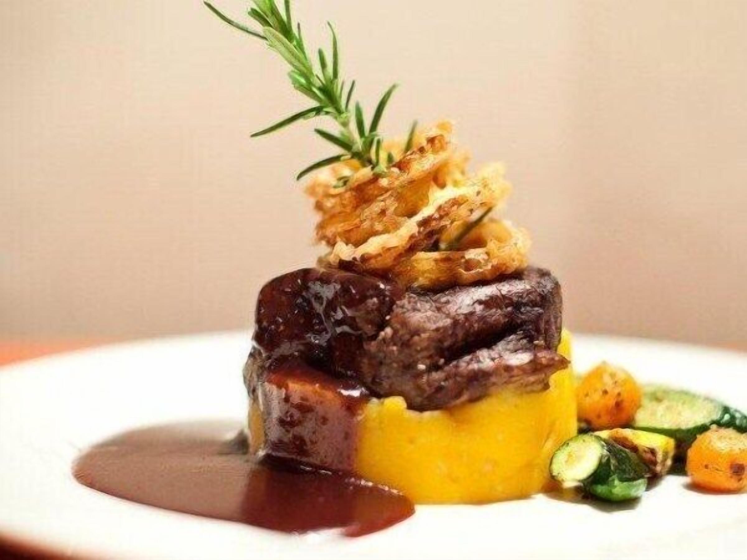 Prato com carne, um molho amarelo e legumes.
