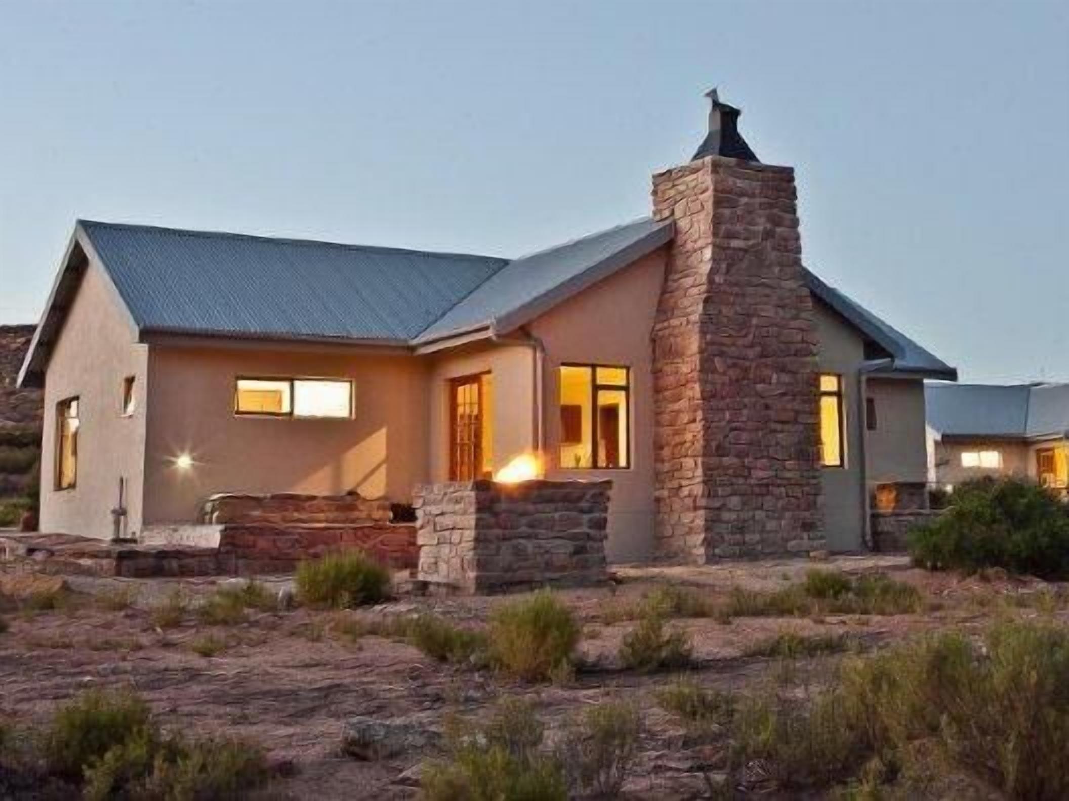 A modern house with a stone chimney, a metal roof, and a well-lit entrance.