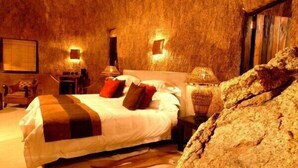Une chambre confortable avec un grand lit, une table de chevet, une lampe et un fauteuil.