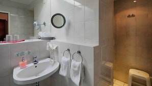 Une salle de bain moderne équipée d’un lavabo, d’un miroir, d’un porte-serviettes et d’un espace douche.