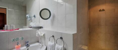 A modern bathroom with a sink, mirror, towel rack, and a shower area.