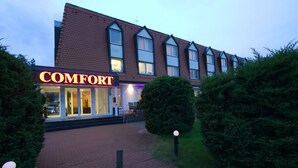 Un hôtel appelé « COMFORT », avec une façade en briques, de grandes fenêtres et une entrée bien éclairée.