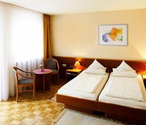 A hotel room with a bed, a chair, a small table, and a painting on the wall. - Weihenstephaner Stuben (Landshut)
