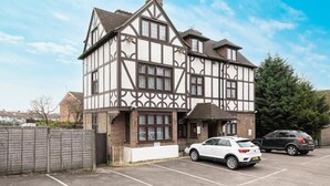 A Tudor-style building with a symmetrical facade, a central entrance, and a parking lot with cars. - Barrington Lodge Hotel  (Crawley)