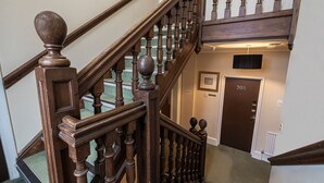 A wooden staircase with a handrail and a door labeled "203" in a hallway. - Barrington Lodge Hotel  (Crawley)