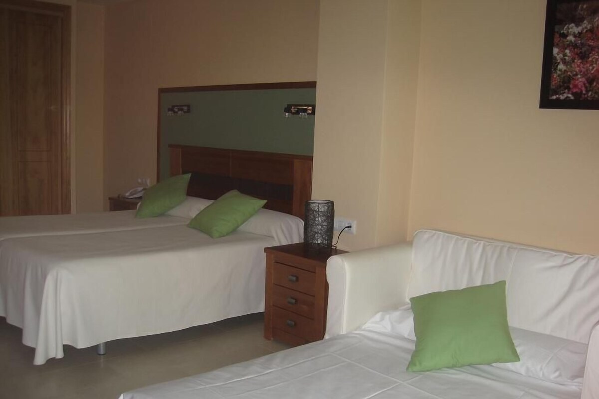 A hotel room with two beds, a nightstand, and a wall-mounted clock.