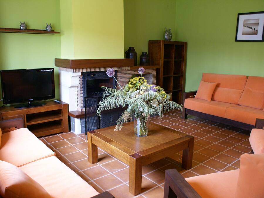 A living room with a wooden coffee table, orange sofa, and a television on a stand.