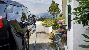 A car charging station with a bicycle parked nearby, surrounded by greenery and a clear view of the landscape. - Hotel Sonnenberg (Kriens)