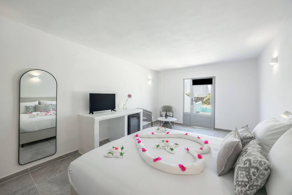 A modern hotel room with a bed, a desk, a TV, and a view of the outdoors.