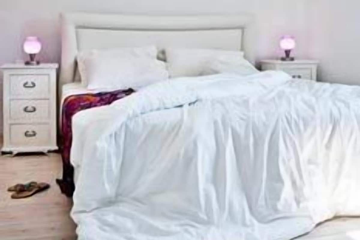A bedroom with a bed, bedside tables, and a hanging light fixture.