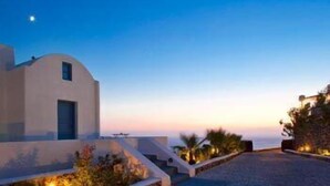 Un edificio blanco con una ventana pequeña y una puerta, sobre un cielo crepuscular.
