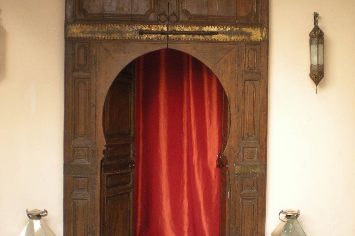 An arched doorway with a red curtain, a hanging lantern, and two lanterns on the floor.