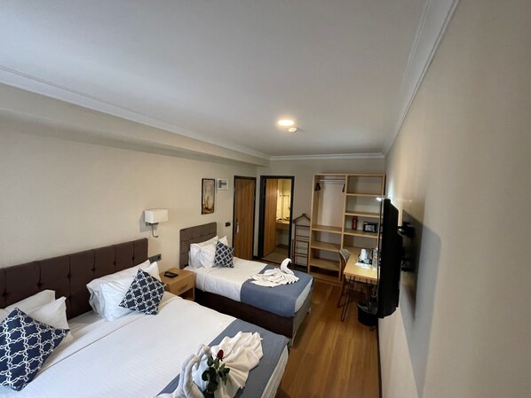 A hotel room with two beds, a desk, a TV, and a wardrobe.