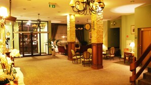A lobby with a carpeted floor, a staircase, and several chairs.