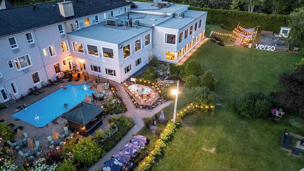Un edificio grande con piscina, zona de estar al aire libre y jardín bien cuidado.