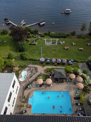 An aerial view of a resort with a swimming pool, outdoor seating, and boats on the water. - Le Manoir Lac-Etchemin (Lac-Etchemin)