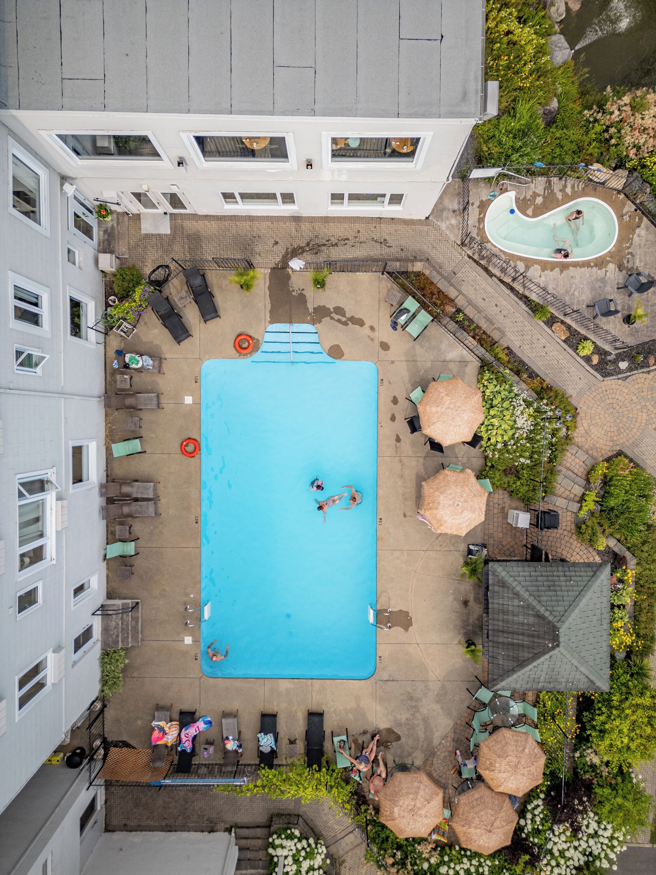 A rooftop pool with a clear blue pool, surrounded by lounge chairs and umbrellas.