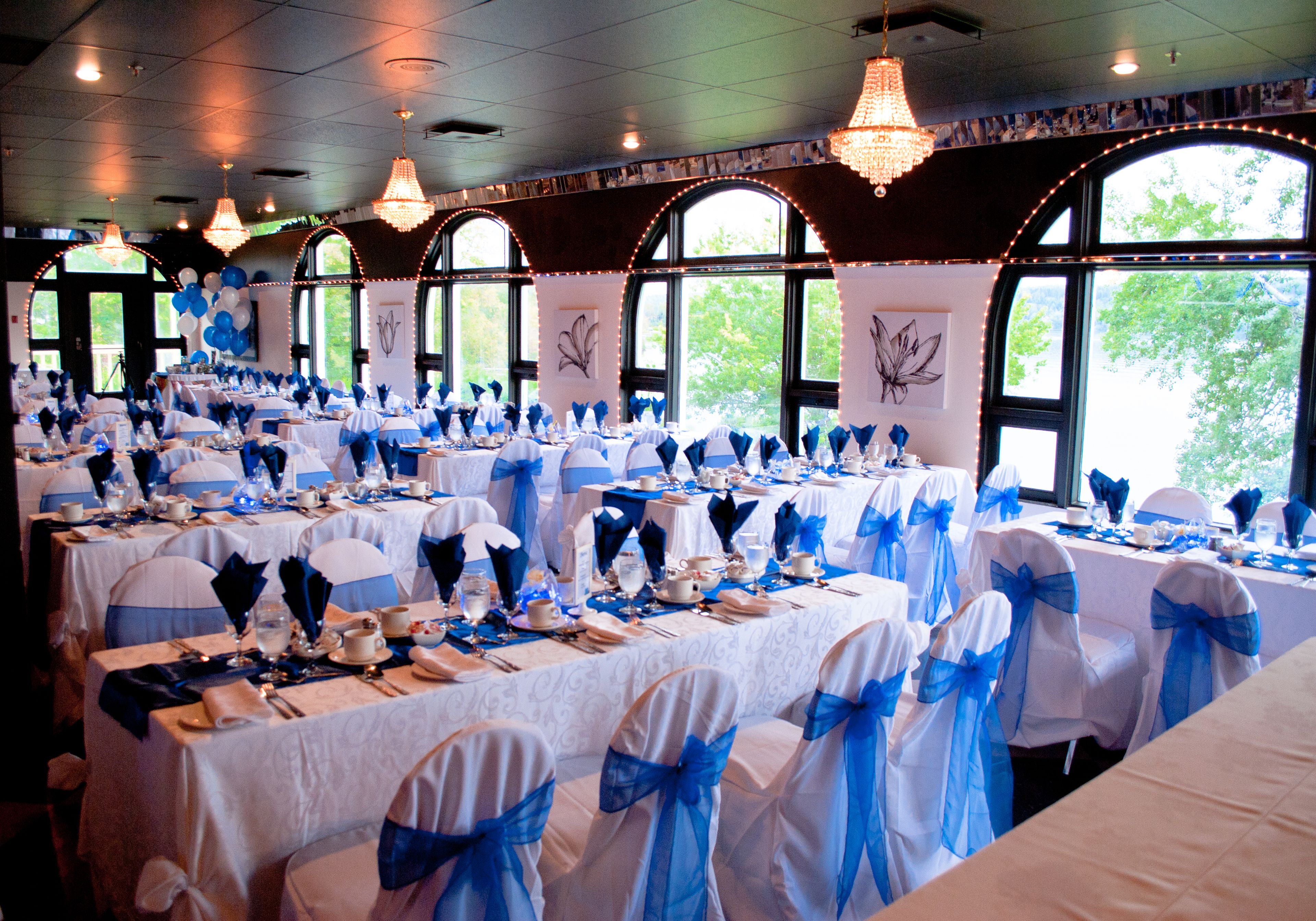 A banquet hall with tables set for a formal event, featuring blue and white decor.