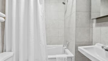 A modern bathroom with a bathtub, a shower, and a sink.