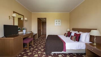 A hotel room with a bed, desk, chair, television, and a door leading to another room.