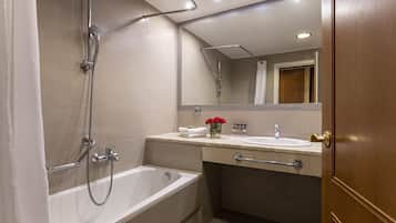 A modern bathroom with a bathtub, shower, vanity, and a mirror.