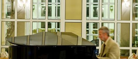 Un piano de cola en una habitación con ventanas amplias y candelabros.