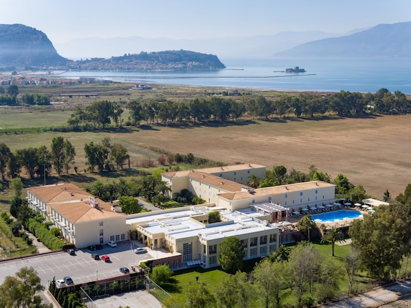 Un hotel con varias edificaciones, piscina y vistas al mar y las montañas.