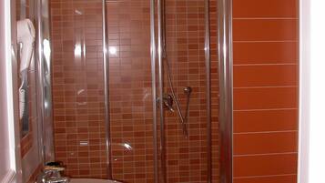 Un baño con ducha de vidrio, lavamanos blanco y un inodoro.