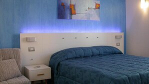 A bedroom with a bed, a nightstand, a chair, and a painting on the wall. - B&B Palazzo Ducale (Andria)
